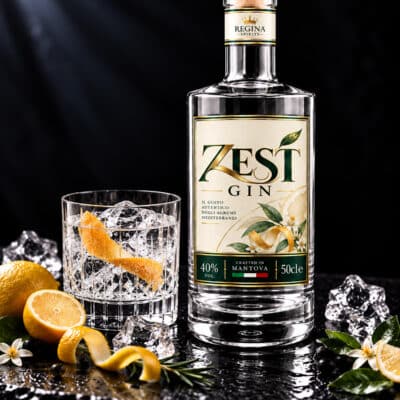 Zest Gin Regina agrumato con bottiglia, bicchiere e agrumi